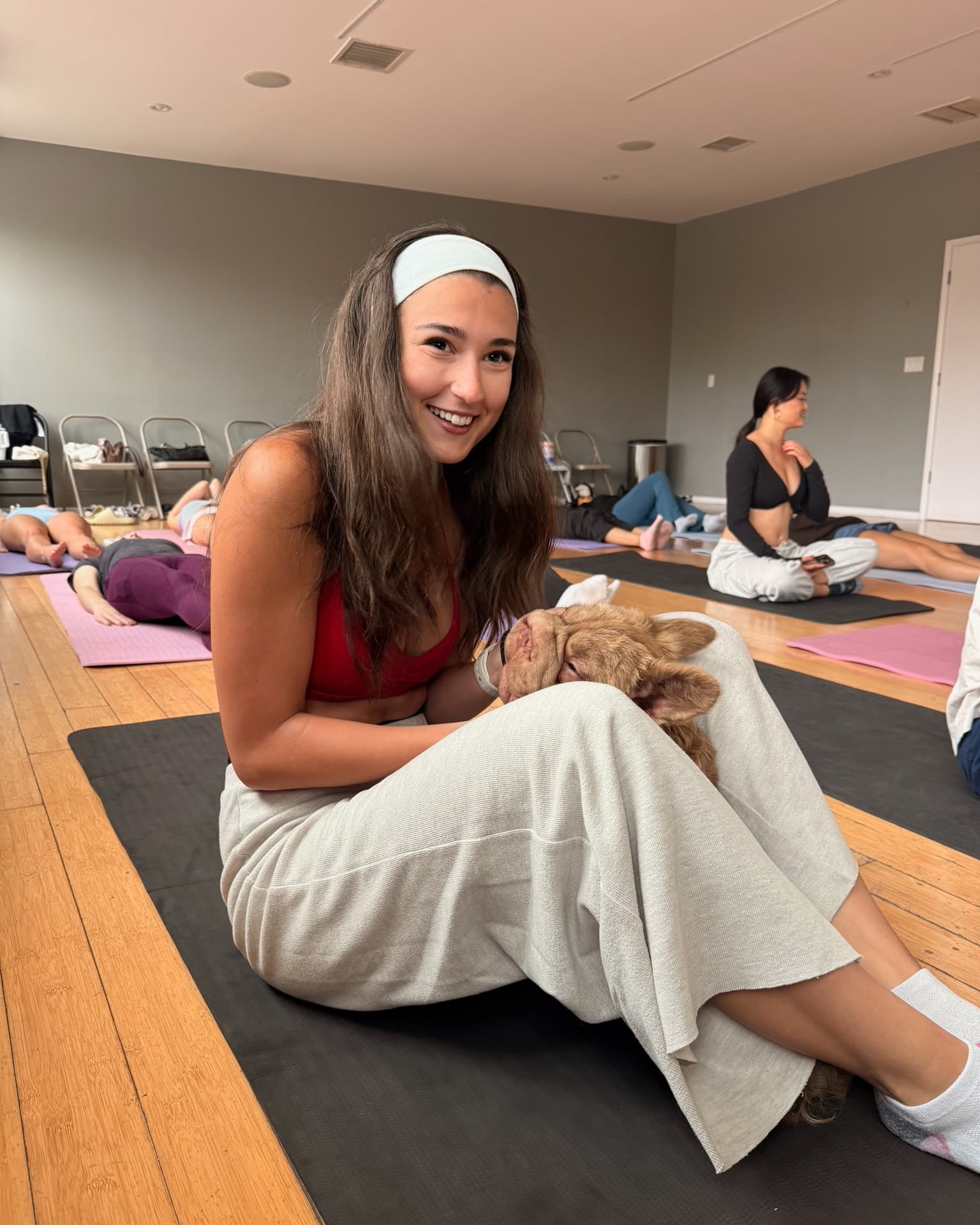 A relaxed guest smiling with a puppy after a gentle yoga class in Westwood