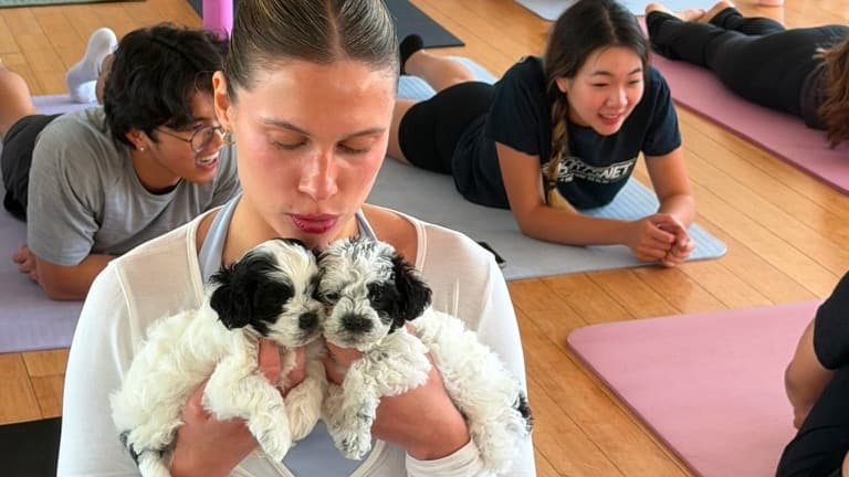 Guest holding two puppies during a Puppy & Flow group experience in Los Angeles