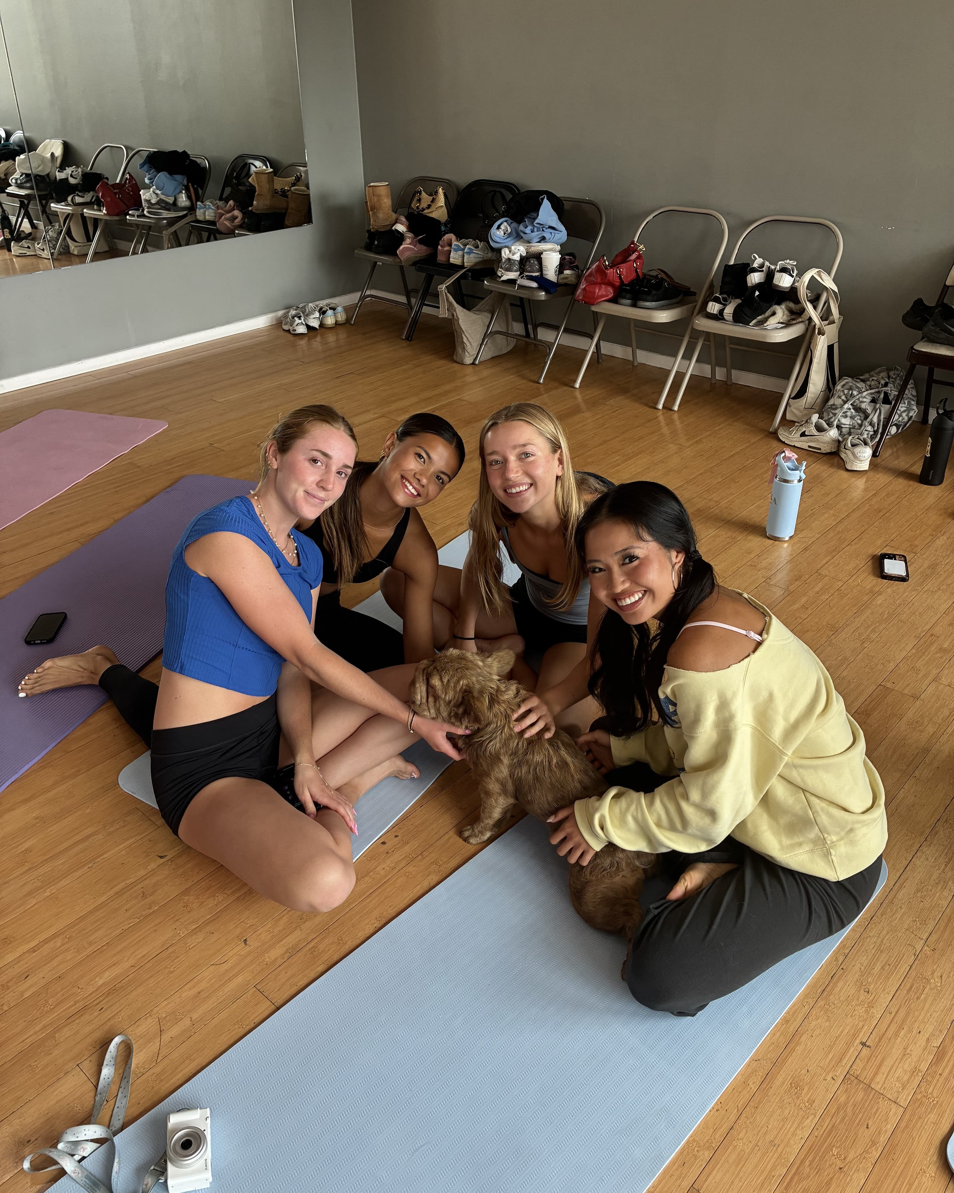 Friends sitting together and playing with a puppy at a Puppy & Flow event